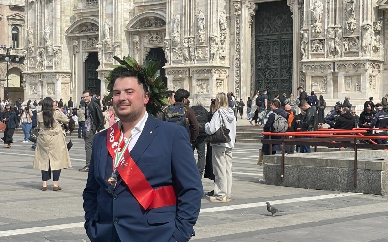 Simone con corona d'alloro davanti al Duomo di Milano dopo la laurea